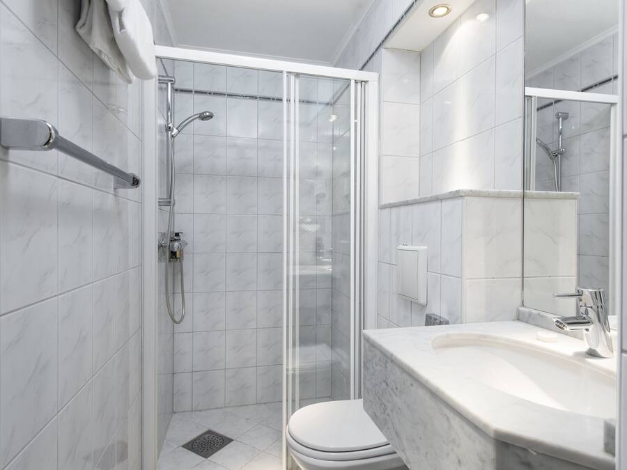 Un baño moderno con ducha de vidrio, inodoro blanco y lavamanos de mármol.