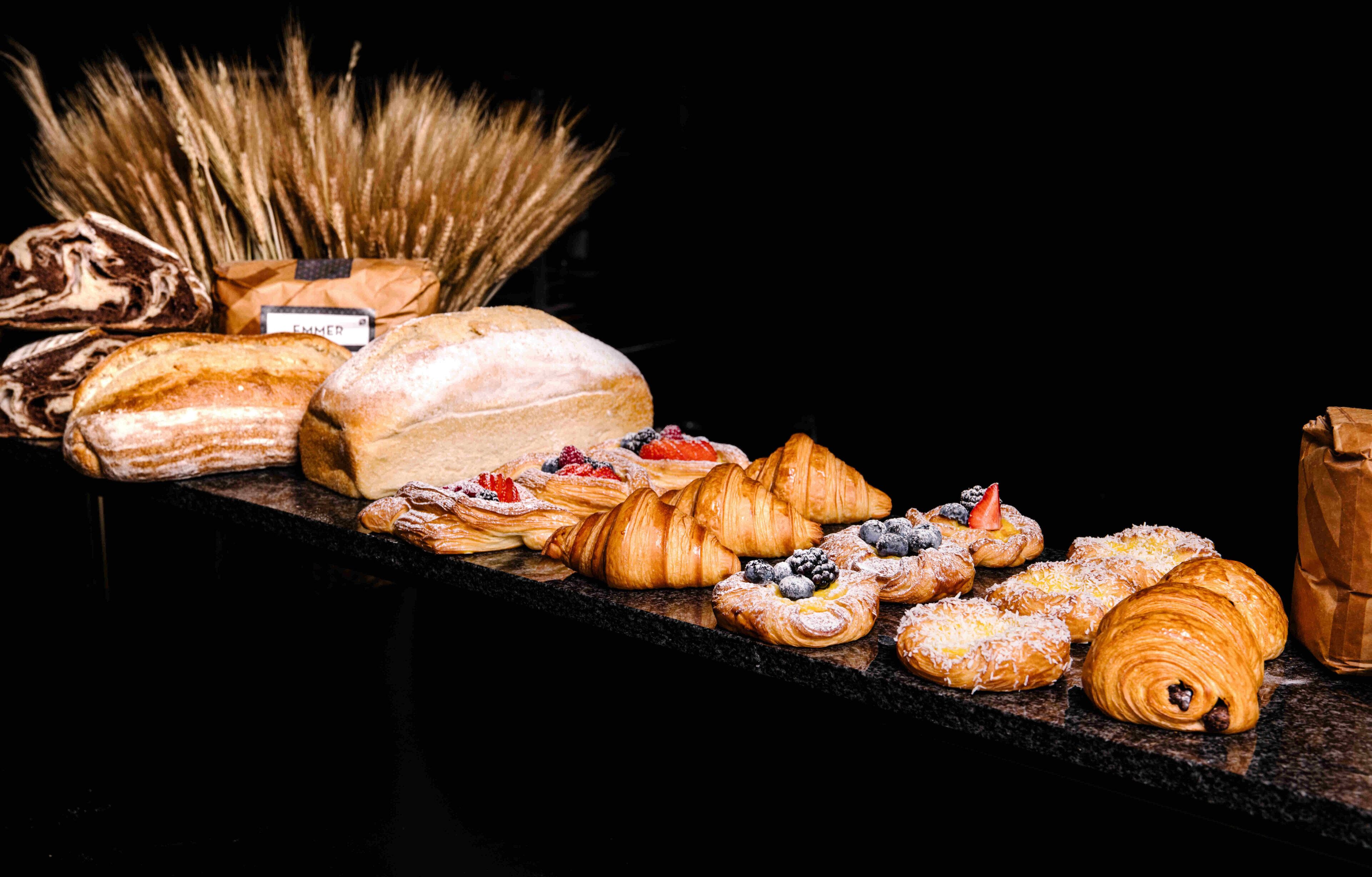 Un assortiment de viennoiseries et de pains est exposé sur un comptoir.