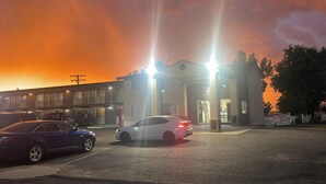 A hotel with a parking lot, a building entrance, and a sunset in the background.
