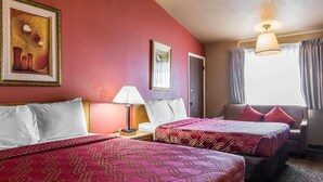 A hotel room with two beds, a nightstand with a lamp, a framed picture on the wall, and a window with curtains.