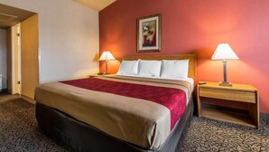 A hotel room with a large bed, two bedside tables, and a painting on the wall.