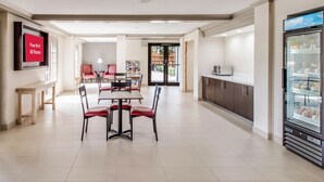 A modern dining area with a flat-screen TV, a refrigerator, and a coffee machine.