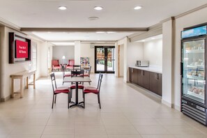 A modern dining area with a flat-screen TV, a refrigerator, and a coffee machine. - Red Roof Inn PLUS+ Dallas – Addison (Addison)