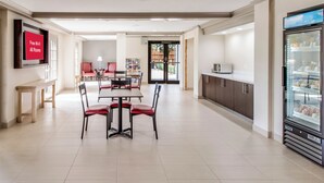 Un comedor amplio con una mesa larga y sillas rojas, un refrigerador con alimentos, y un letrero que indica Wi-Fi gratuito en todas las habitaciones.