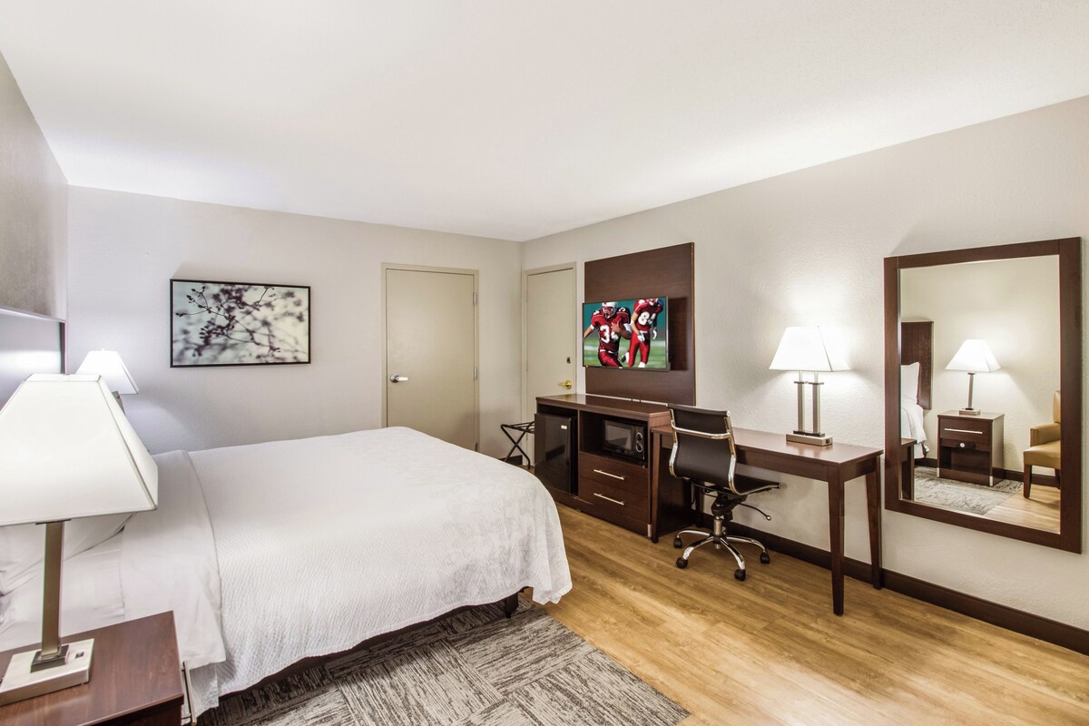 A hotel room with a bed, desk, chair, and a television.