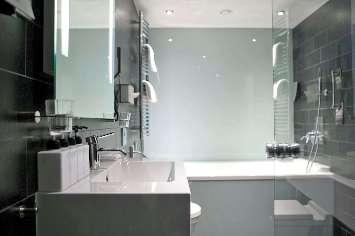 A modern bathroom with a large mirror, a sink, and a glass-enclosed shower area.