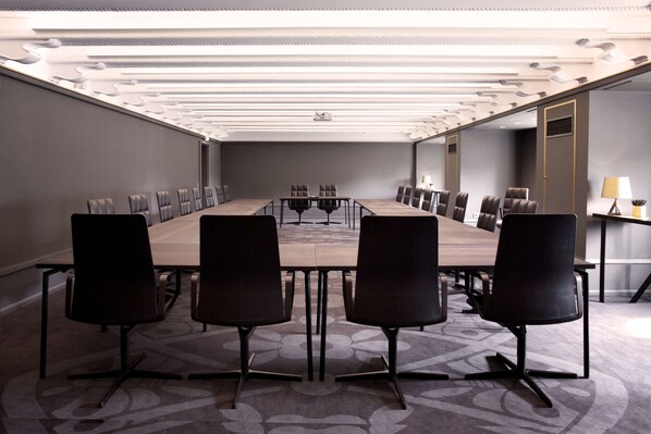 A conference room with a long table, multiple chairs, and a modern ceiling design.
