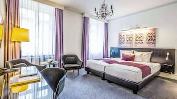 Et hotelværelse med seng, skrivebord, stol og et lille bord.
