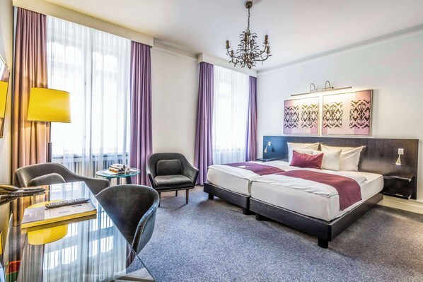 Una habitación de hotel con cama, escritorio, silla y una mesita.