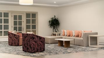 A modern living room with a sofa, two armchairs, a coffee table, and a large potted plant.