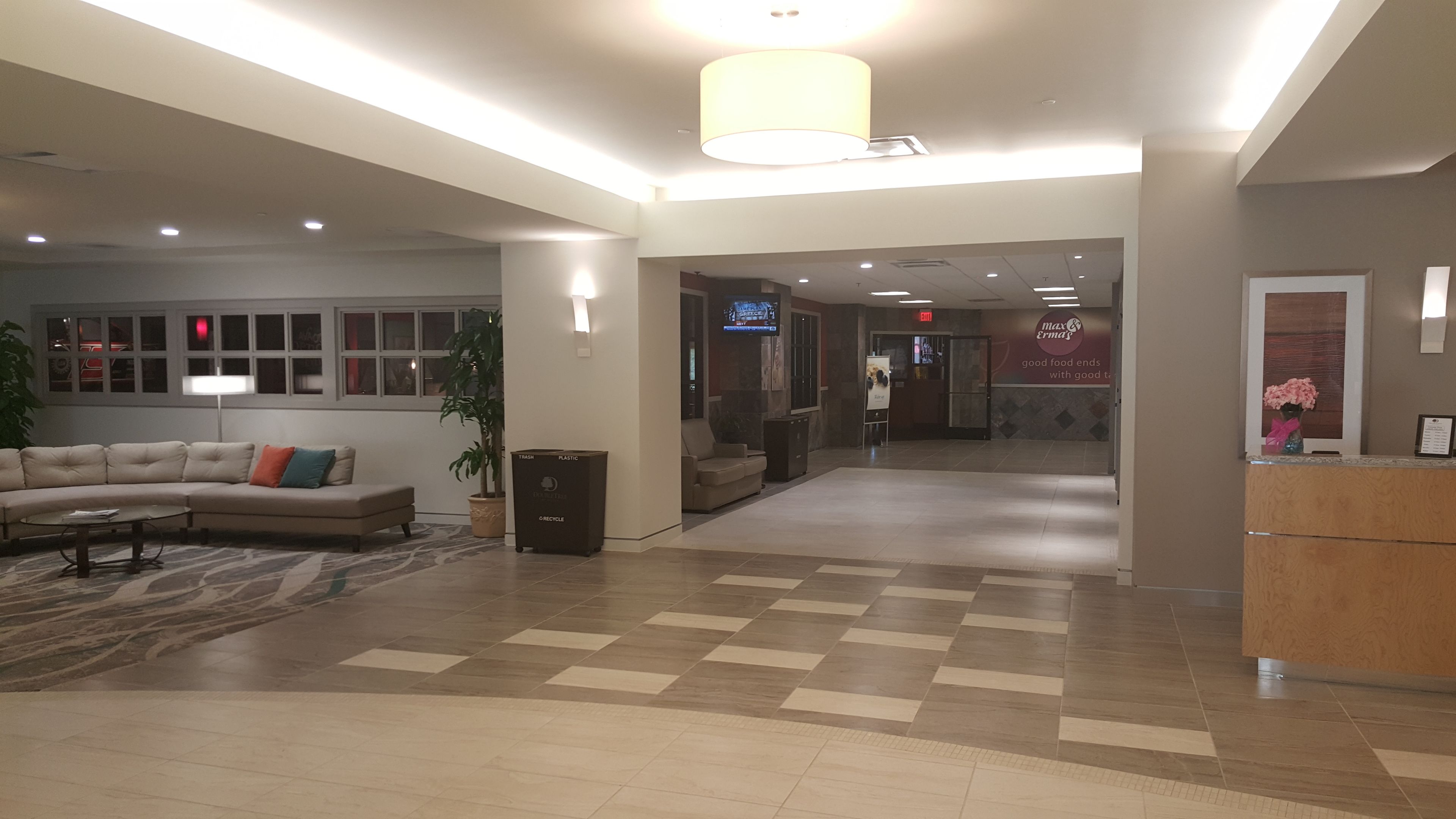 Un'ampia hall con pavimento a scacchi, un divano, un cestino e una reception.