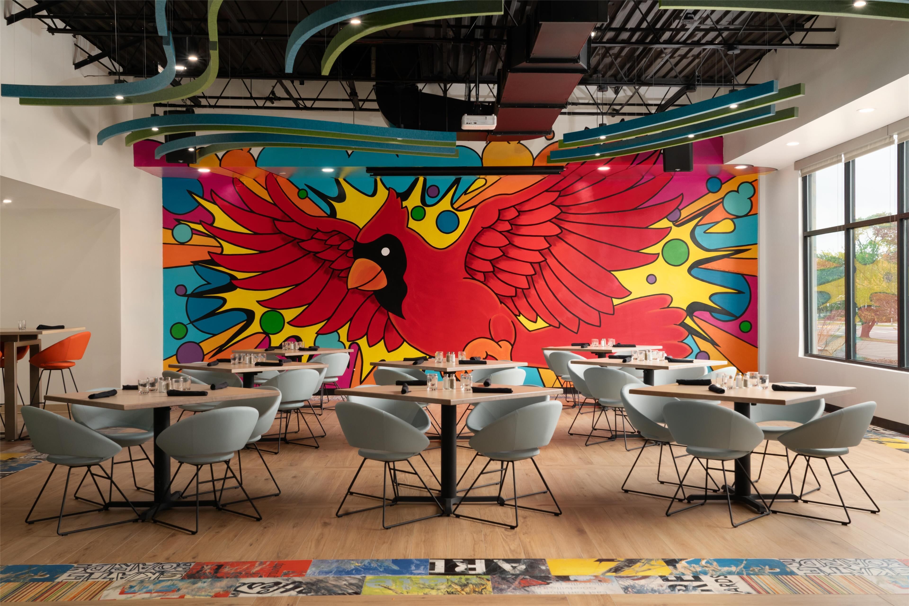A modern dining area with colorful murals, contemporary furniture, and large windows.