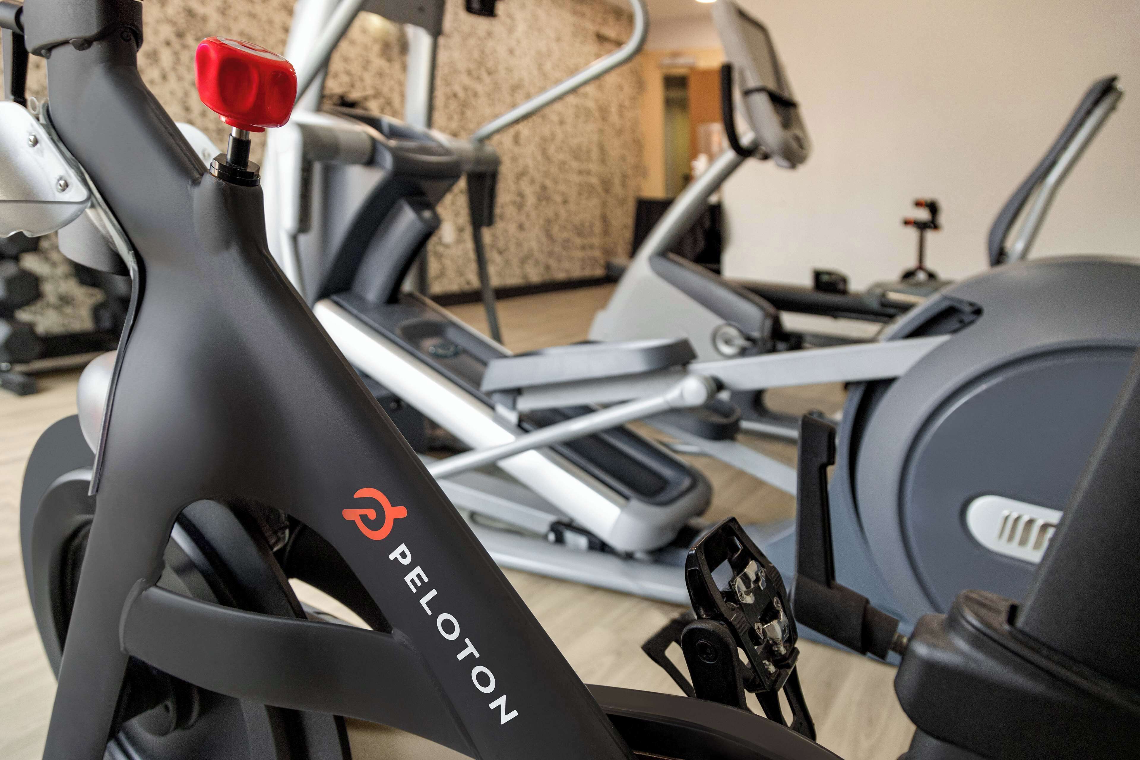 Uma bicicleta de exercício Peloton numa academia, com outros equipamentos de ginástica.