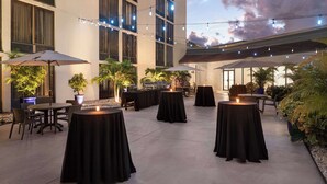 An outdoor patio area with tables and chairs, string lights, and potted plants. - Doubletree by Hilton Fort Myers at Bell Tower Shops (Fort Myers)