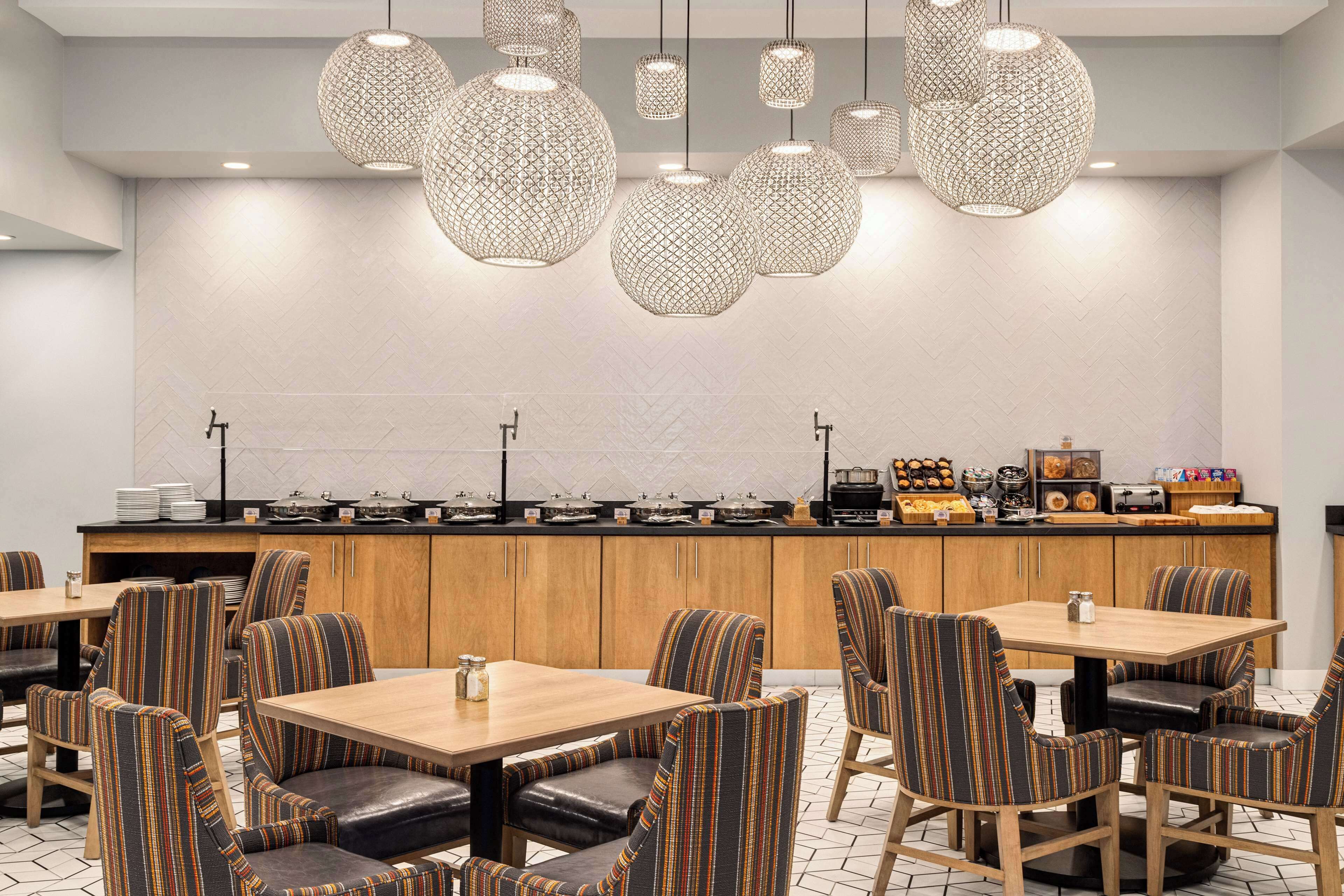 A restaurant with striped chairs, a wooden table, and a counter with food items.