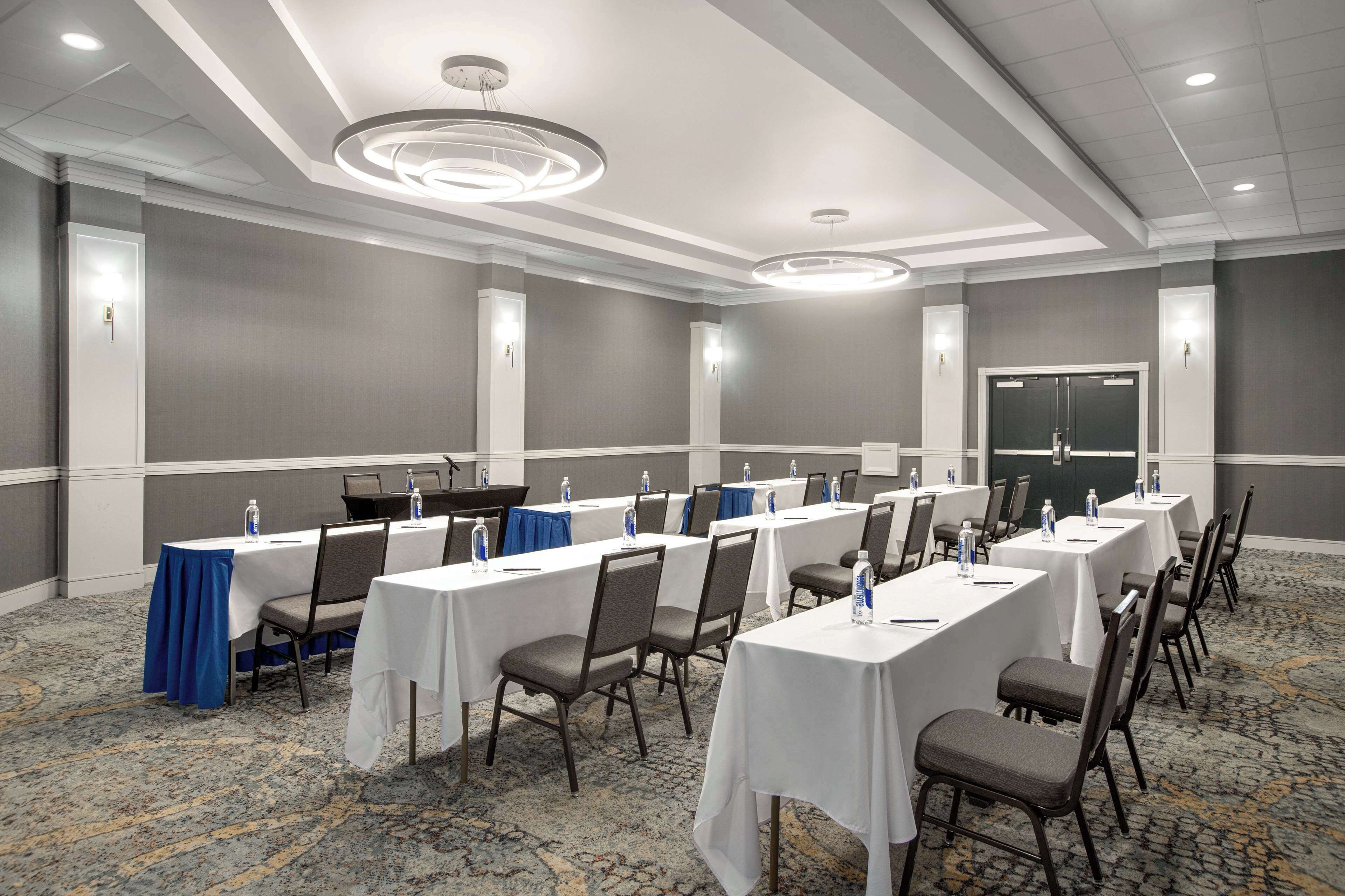A conference room with multiple tables, chairs, and water bottles.