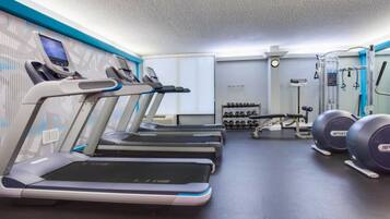 Un gimnasio con cintas de correr, mancuernas y máquinas de pesas.
