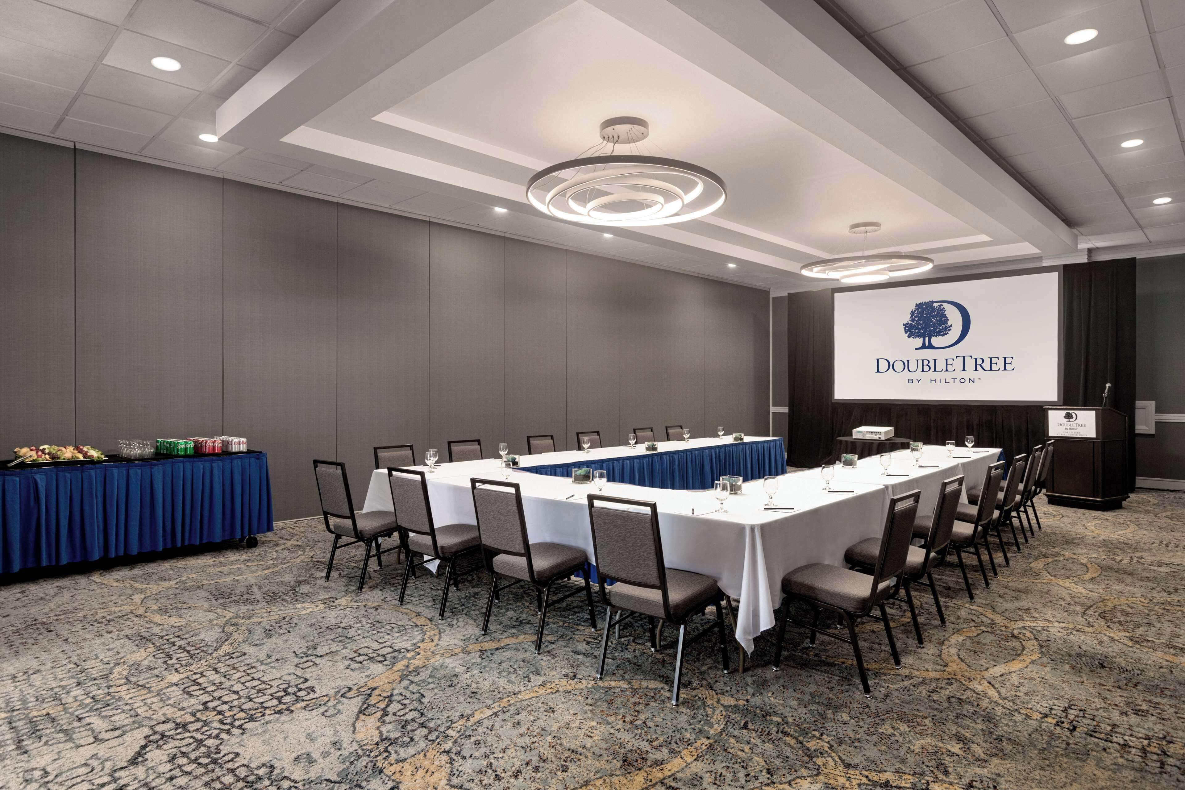 A conference room with a long table, chairs, and a podium.