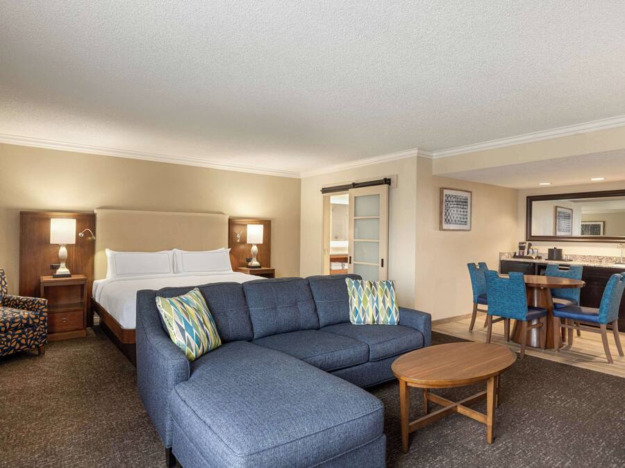 Ein Hotelzimmer mit einem großen Bett, einer Couch, einem Esstisch und einer Küchenzeile.