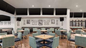 A restaurant with multiple tables and booths, framed pictures on the walls, and a pool table in the background.