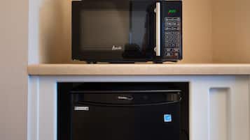 Un microondas negro sobre una encimera blanca con un refrigerador negro debajo.