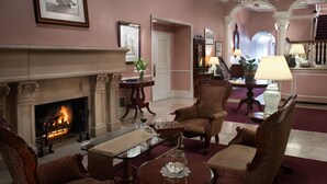 A formal living room with a fireplace, elegant furniture, and a chandelier. - The Monterey Hotel (Monterey)