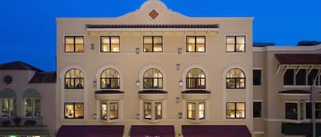 A multi-story hotel with a central entrance, large windows, and a red awning.