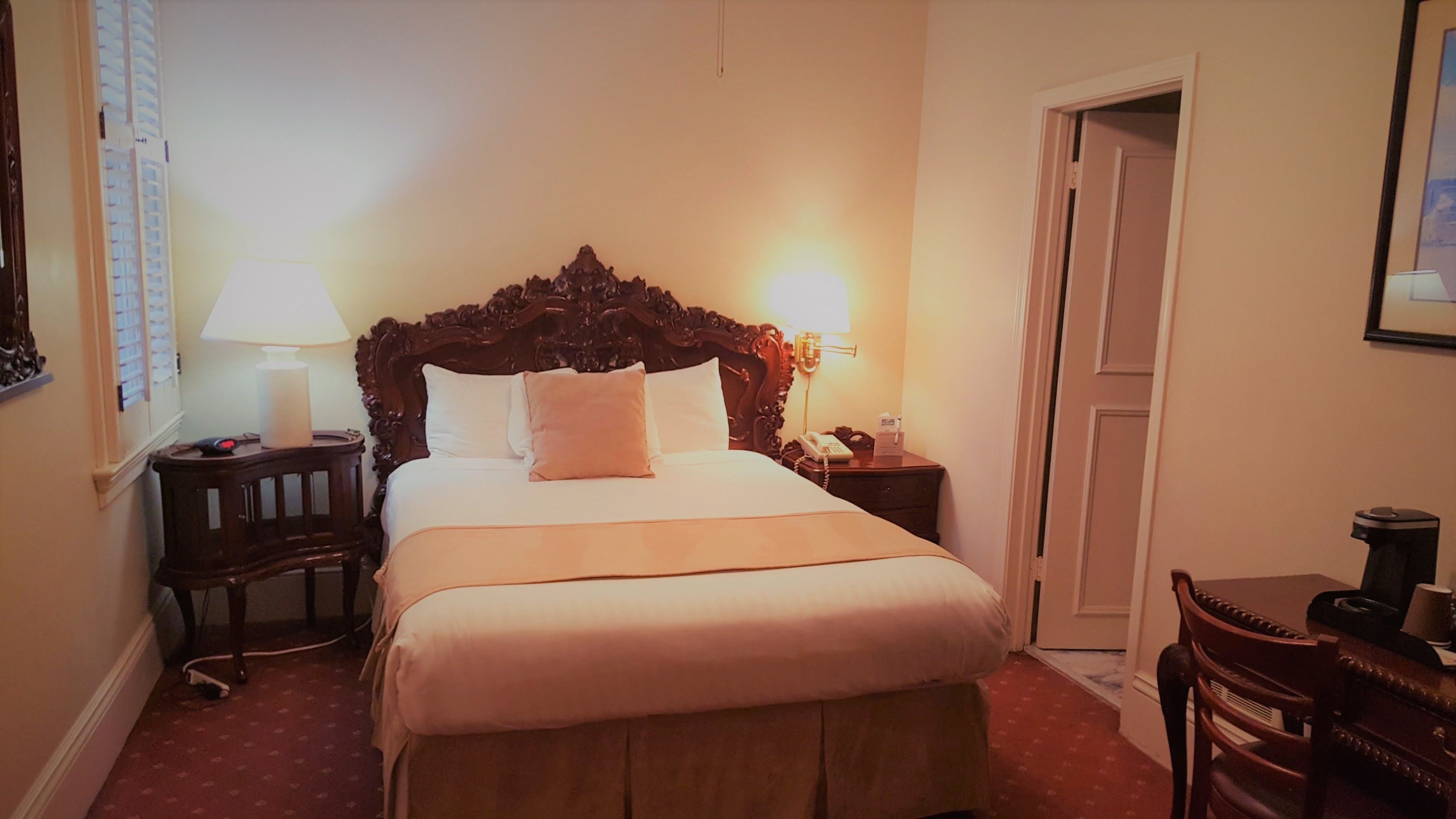 Ein Hotelzimmer mit einem großen Bett, Nachttischlampen, einem Schreibtisch und einem Sessel.