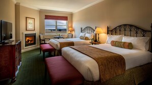 A hotel room with two beds, a fireplace, a television, and a view of the outside.