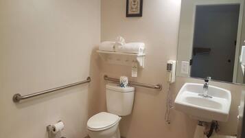 A bathroom with a toilet, a sink, a hand dryer, and a towel rack.