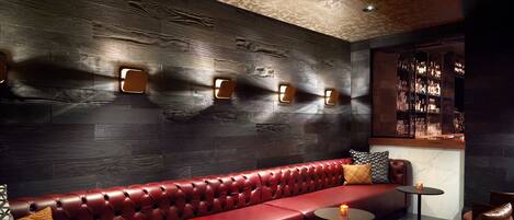 Un coin salon en cuir rouge avec un bar en arrière-plan.