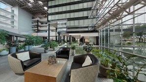 A spacious indoor area with multiple seating arrangements, large windows, and potted plants.