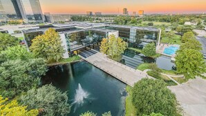 A modern building with a glass facade, a central courtyard with a fountain, and a swimming pool.