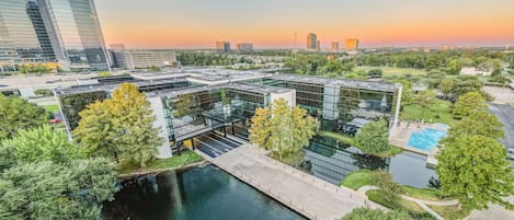 A modern building with a glass facade, a central courtyard with a fountain, and a swimming pool.