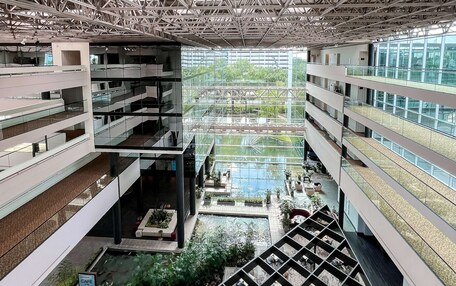 A multi-level atrium with a central water feature, glass railings, and outdoor seating areas.