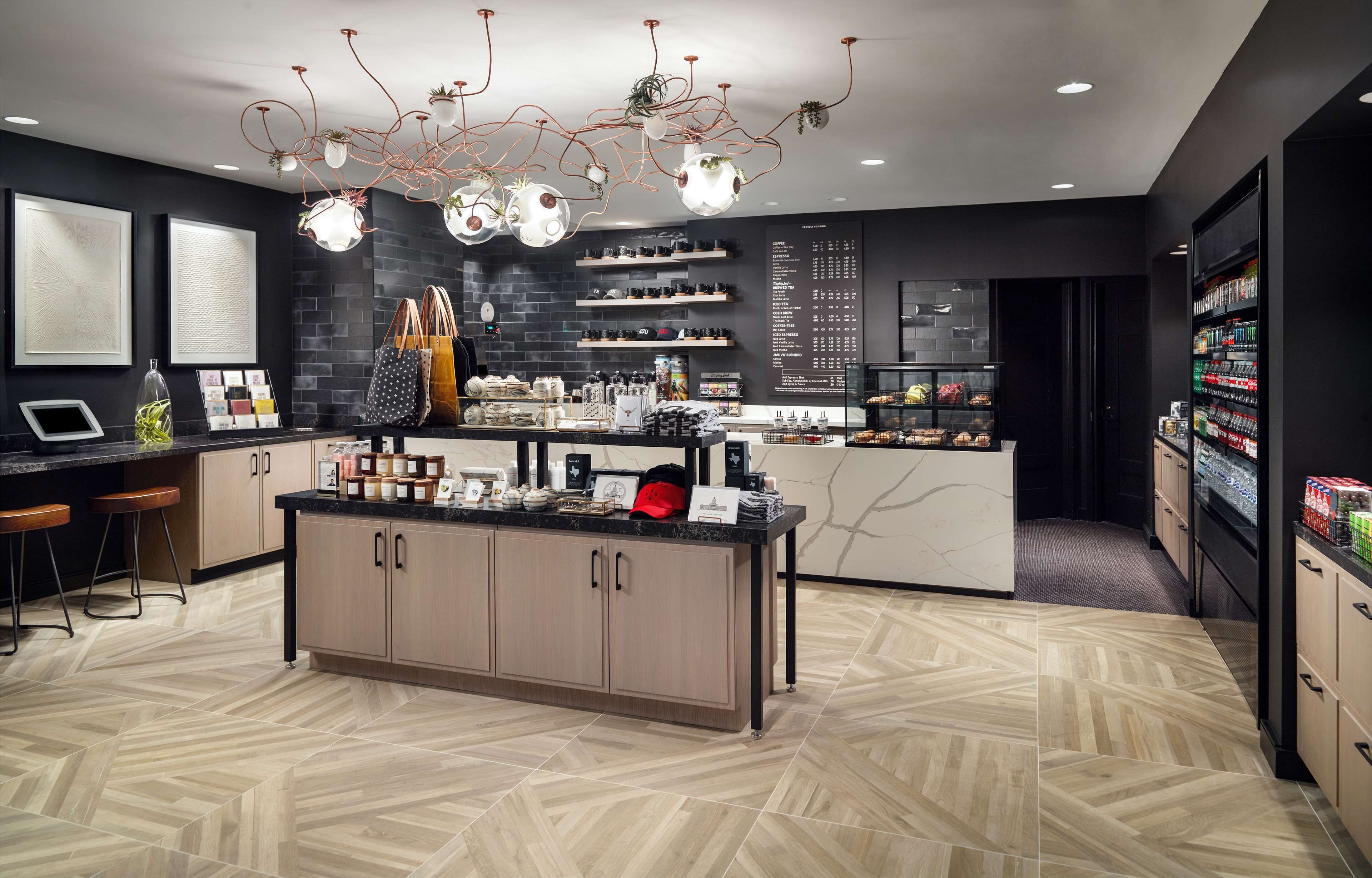 Una cocina moderna con una isla central, estanterías negras y una lámpara decorativa en el techo.