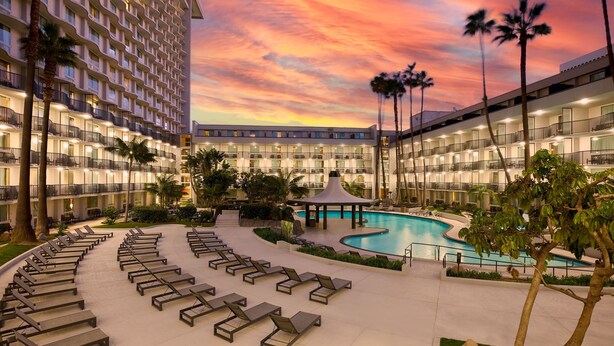Un hôtel doté d’une piscine, de chaises longues et de palmiers.