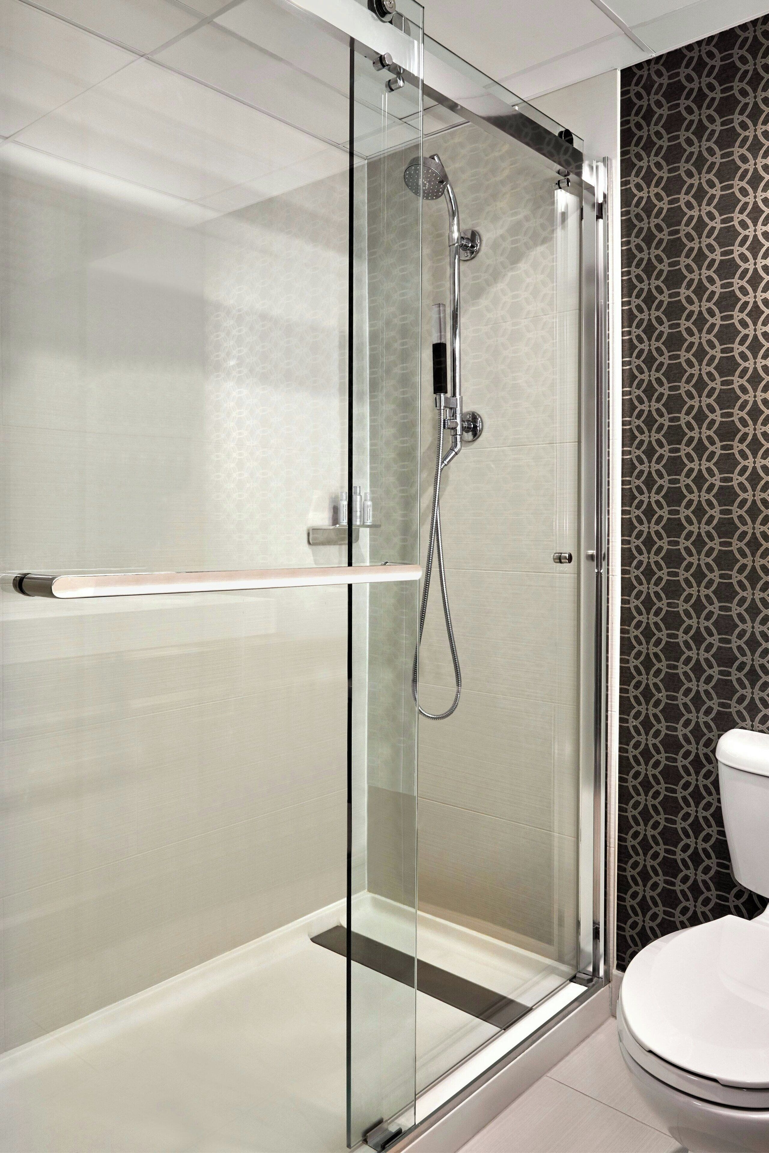A modern bathroom with a glass-enclosed shower, a white toilet, and a patterned wall.