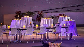 A dining area with tables set for guests, featuring white tablecloths and candle centerpieces.