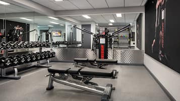 A gym with weightlifting equipment, benches, and dumbbells.