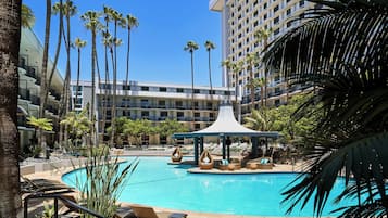 Relax by the serene pool surrounded by palm trees and lounge chairs.