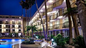 Un hôtel doté de nombreux balcons, d’une piscine et de palmiers.