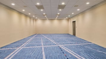 Habitación de hotel con un amplio suelo alfombrado, una puerta e iluminación empotrada en el techo.