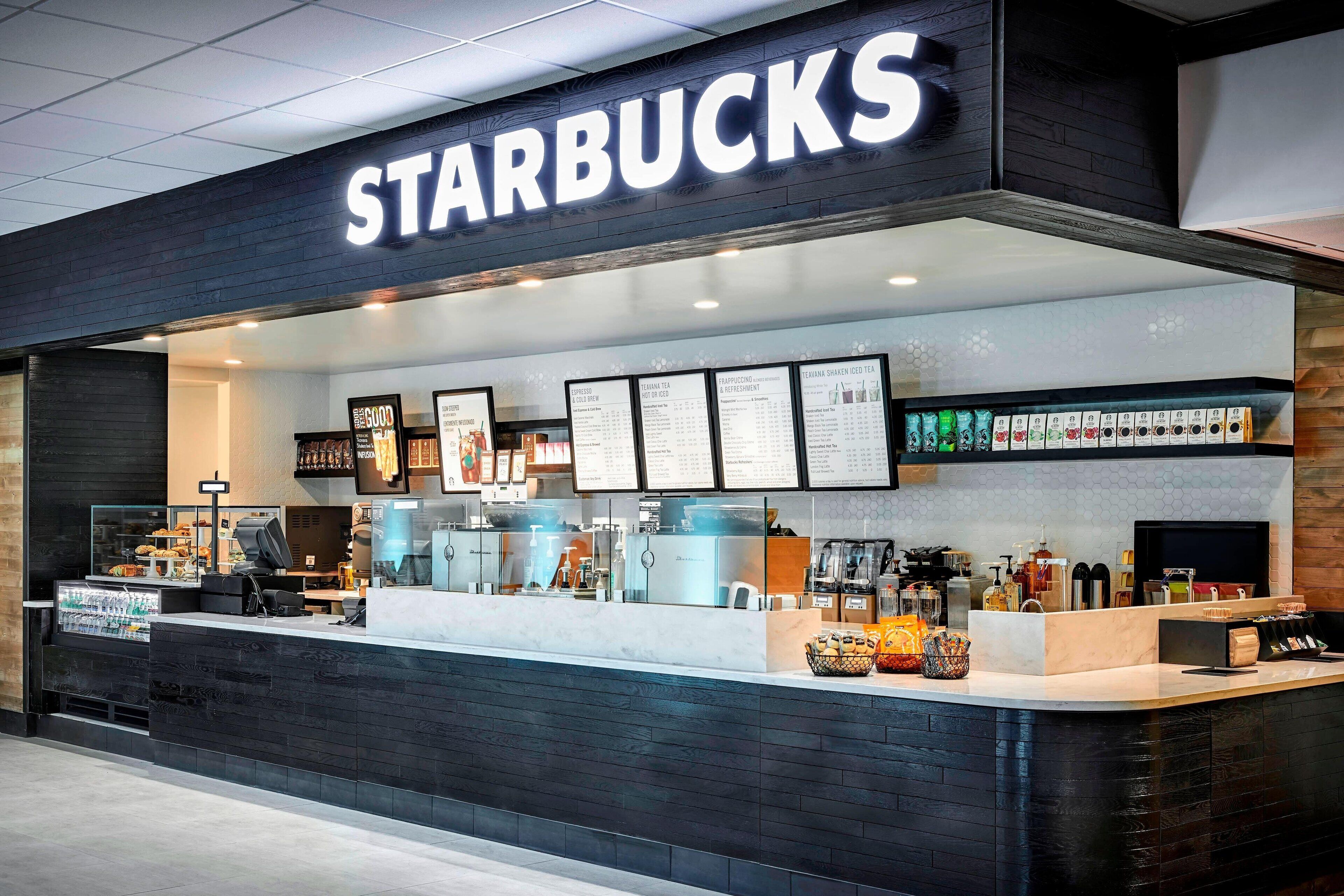 A Starbucks store with a modern design, featuring a counter with a menu display, a variety of coffee machines, and a selection of beverages and snacks.