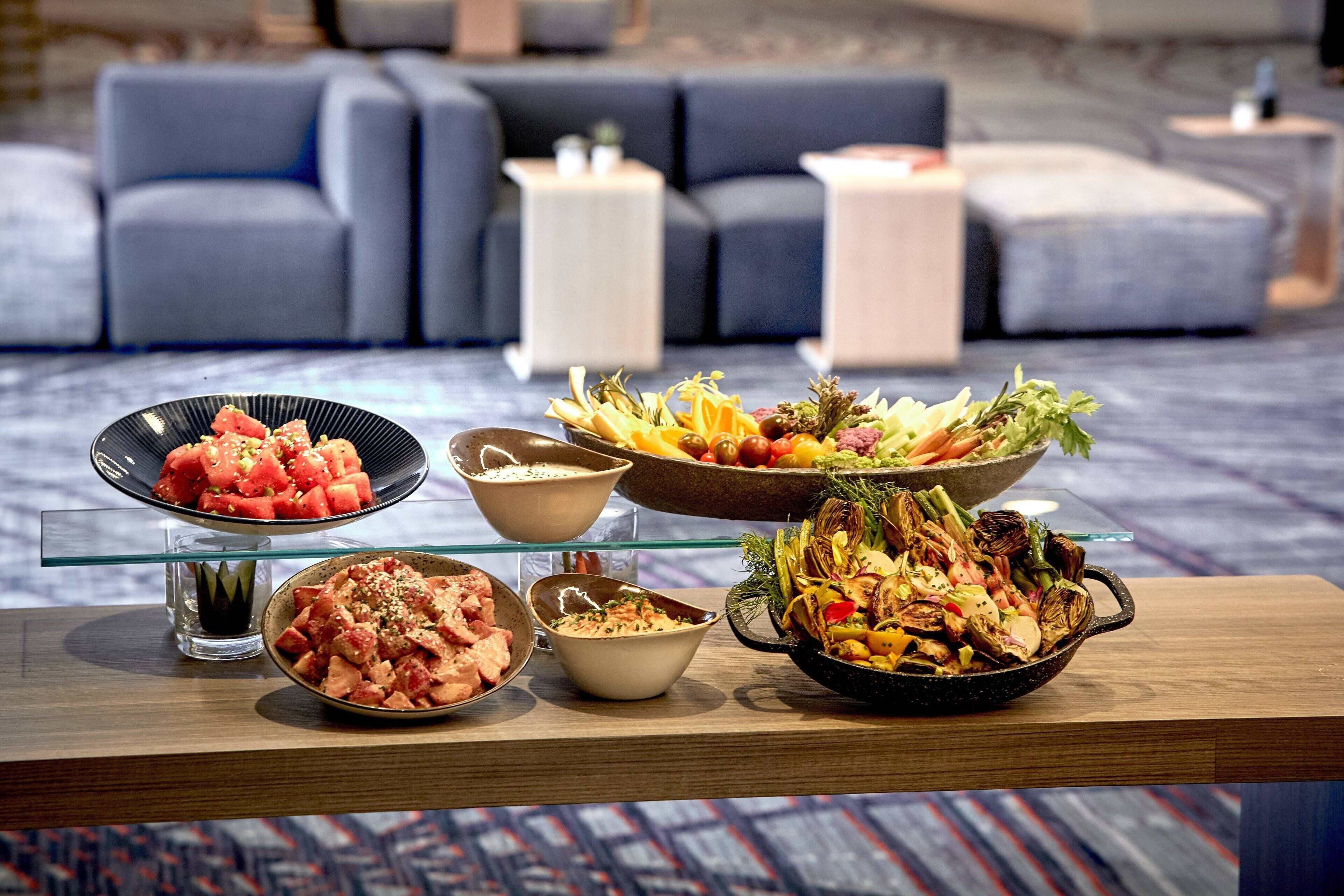 A dining table with various dishes, a sofa, and a small side table in a modern living area.