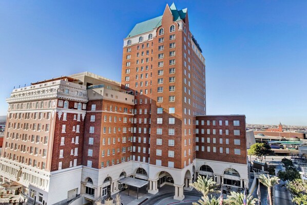 A multi-story hotel with a prominent red brick facade, large windows, and a green roof. - Hotel Paso Del Norte, Autograph Collection (El Paso)