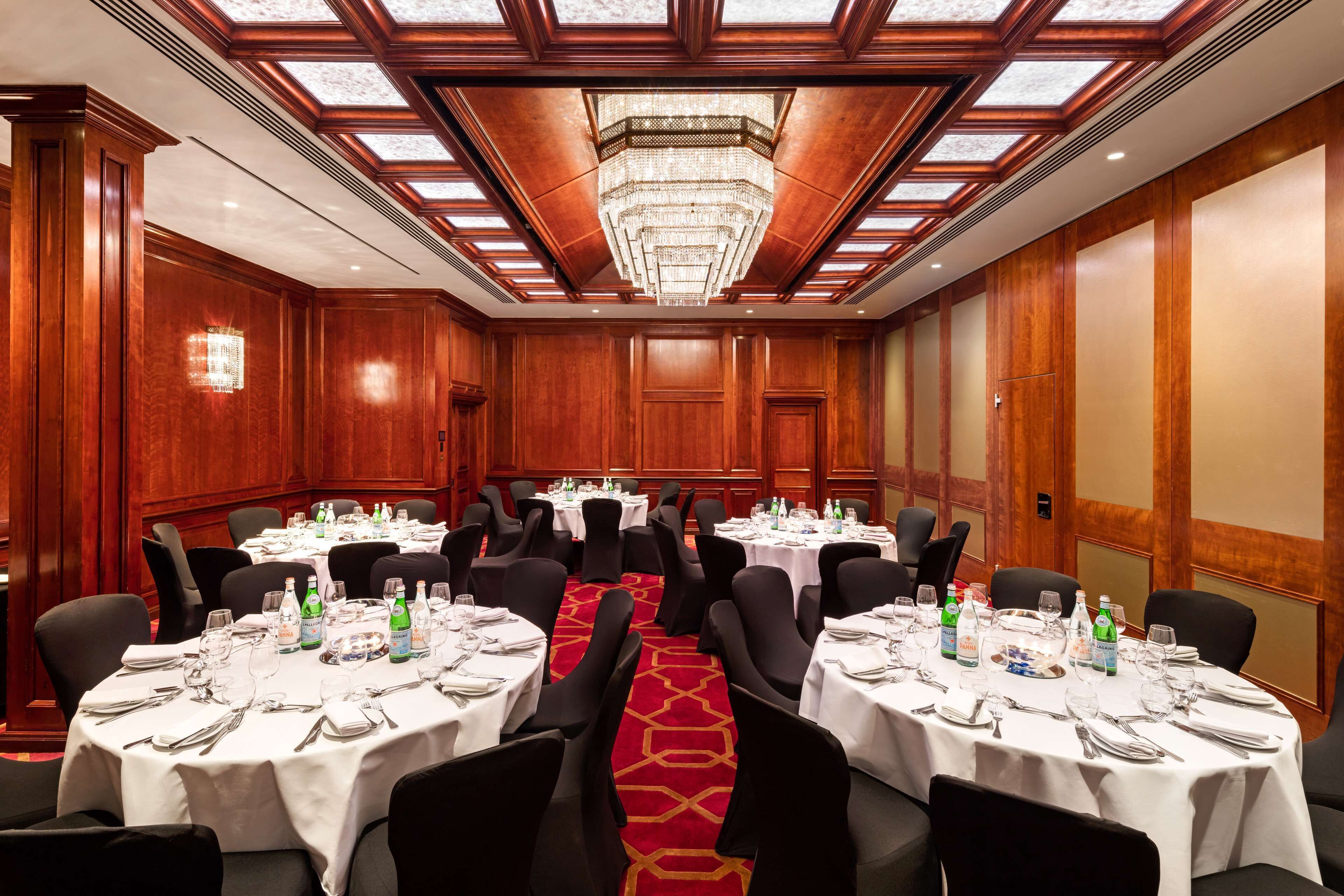 A conference room with multiple tables set for a meeting, equipped with water bottles, glasses, and cutlery.