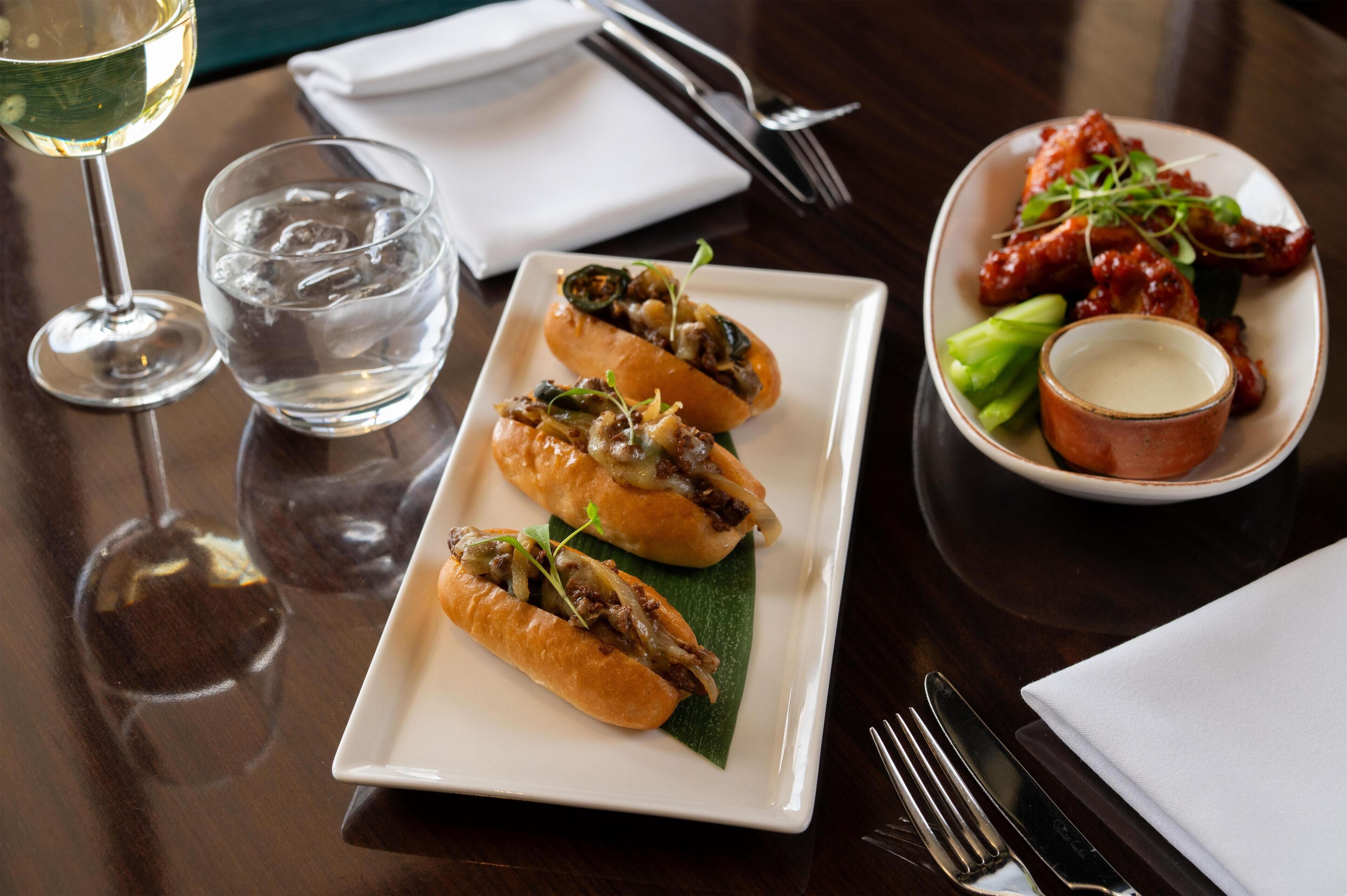 A dining table with a plate of food, a glass of water, and a glass of wine.