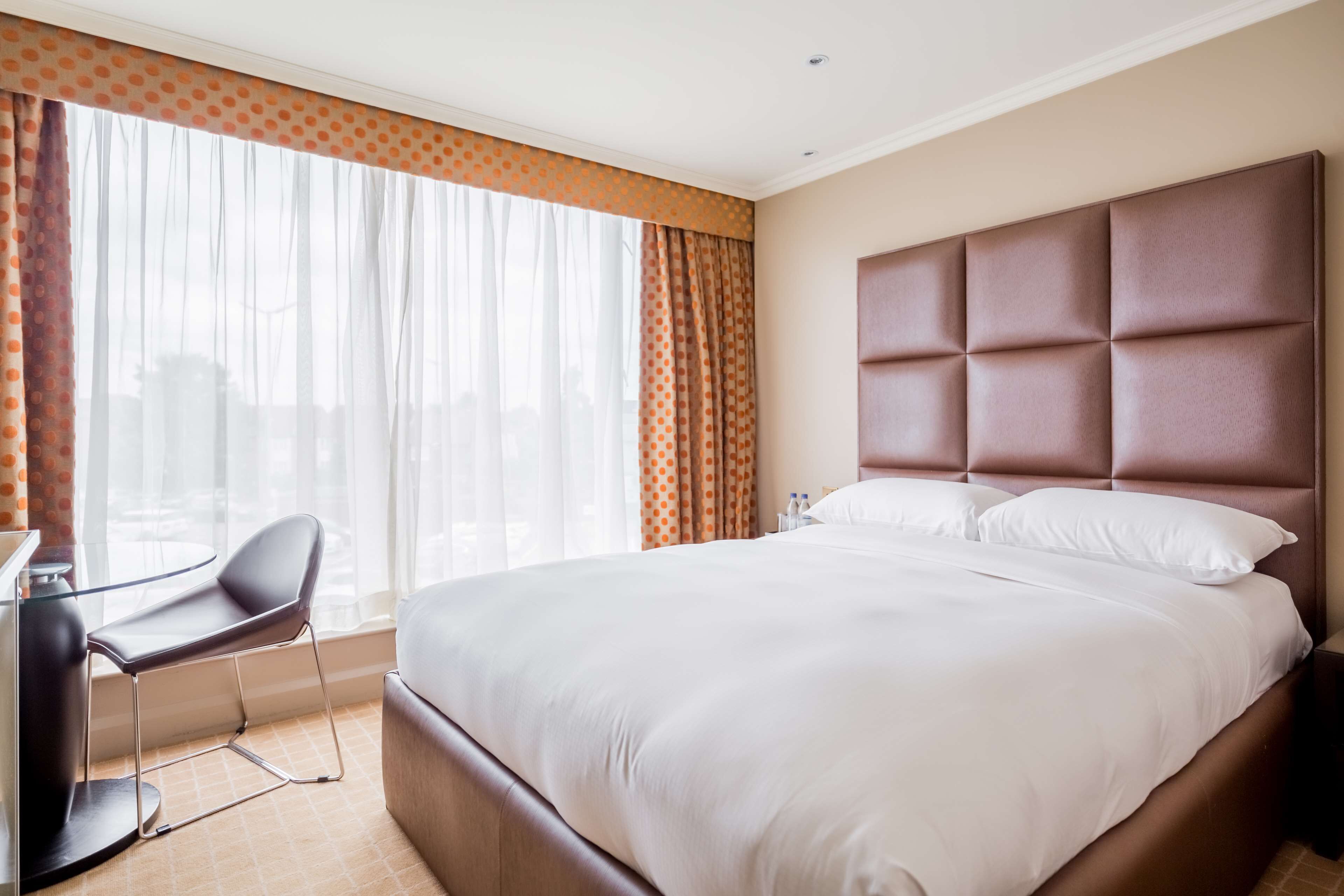 A hotel room with a large bed, a desk, and a chair.