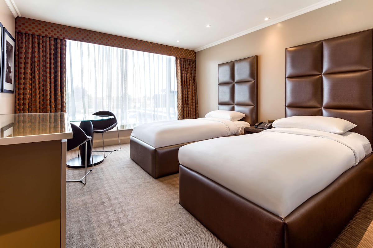 A hotel room with two beds, a desk, and a chair.